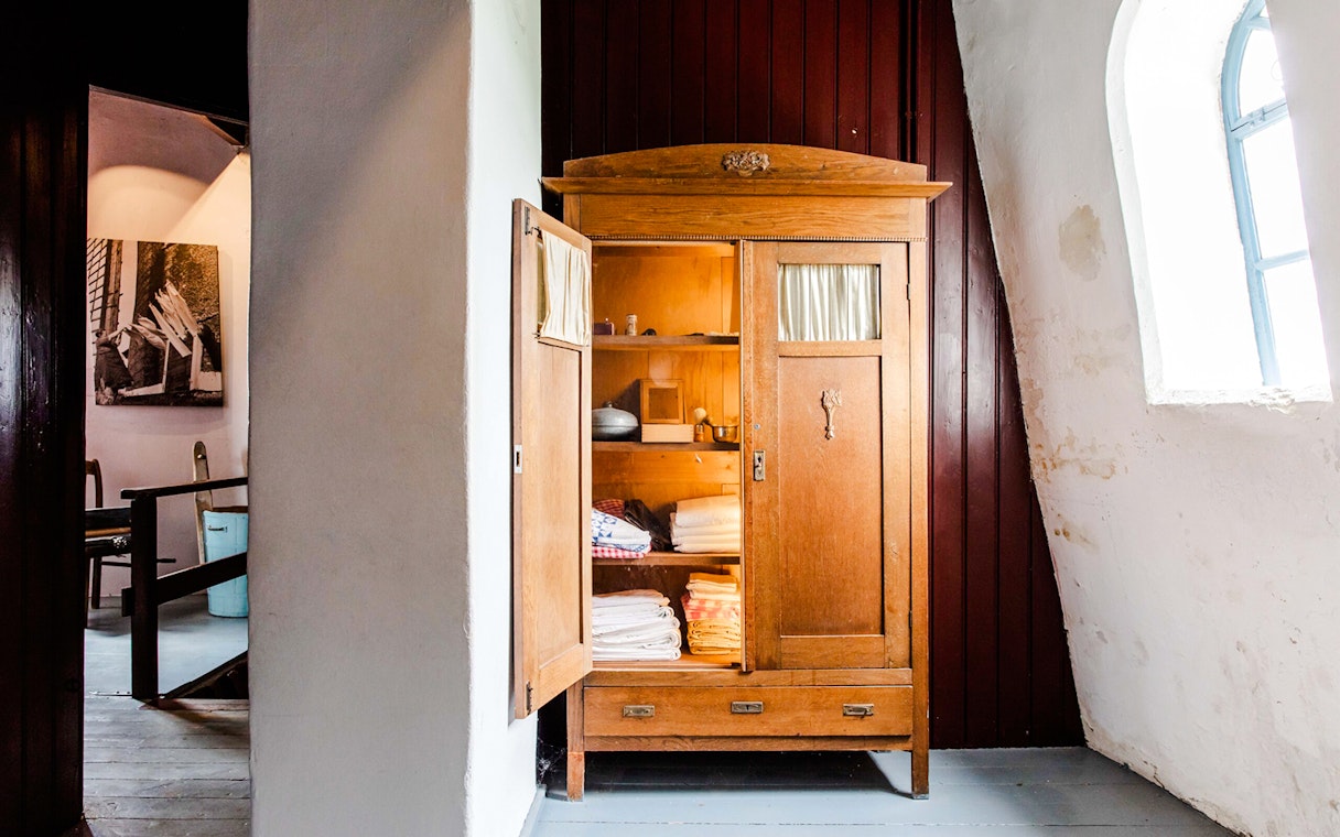 Open wooden cabinet with linens inside at Nederwaard Museum Mill, Kinderdijk.