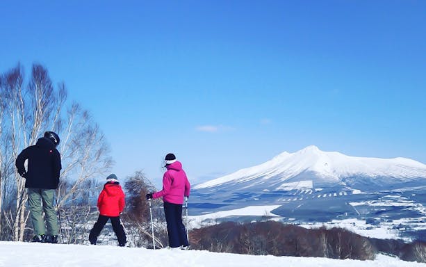 Skiers overlooking snowy landscape at Greenpia Onuma Ski Resort, Japan.