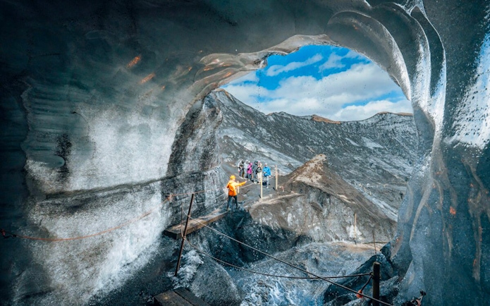 Guests exploring inside Katla Ice Cave in Iceland with guide.