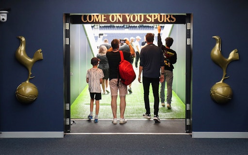 Visitors entering Tottenham Hotspur Stadium tunnel with "Come On You Spurs" sign.