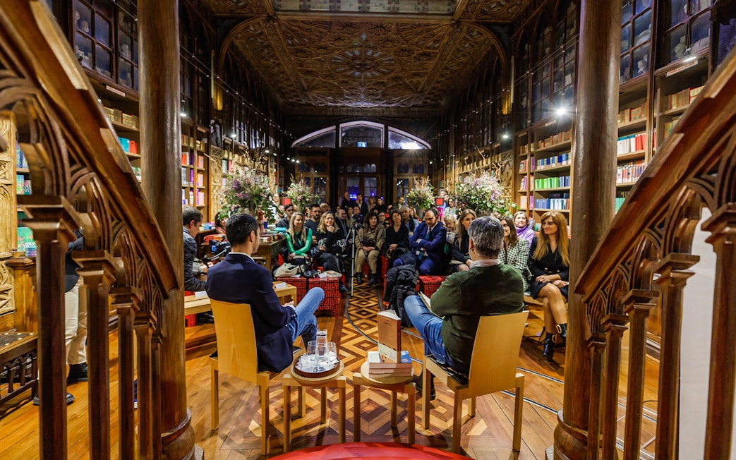 Audience attending a conference at Lello Library, Porto, surrounded by ornate wooden shelves and books.