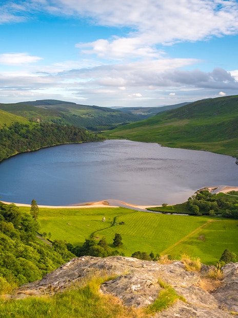 Lough Tay lake surrounded by lush greenery in Wicklow Mountains, Ireland.