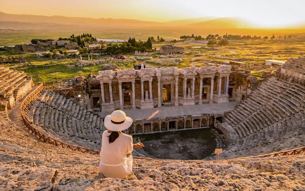 Woman sitting in Hierapolis amphitheater overlooking ruins, Antalya Pamukkale day trip.