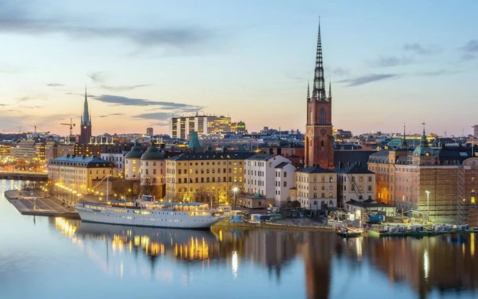 Stockholm cityscape with Riddarholmen Church at sunset, part of the Royal Vikings exploration game.