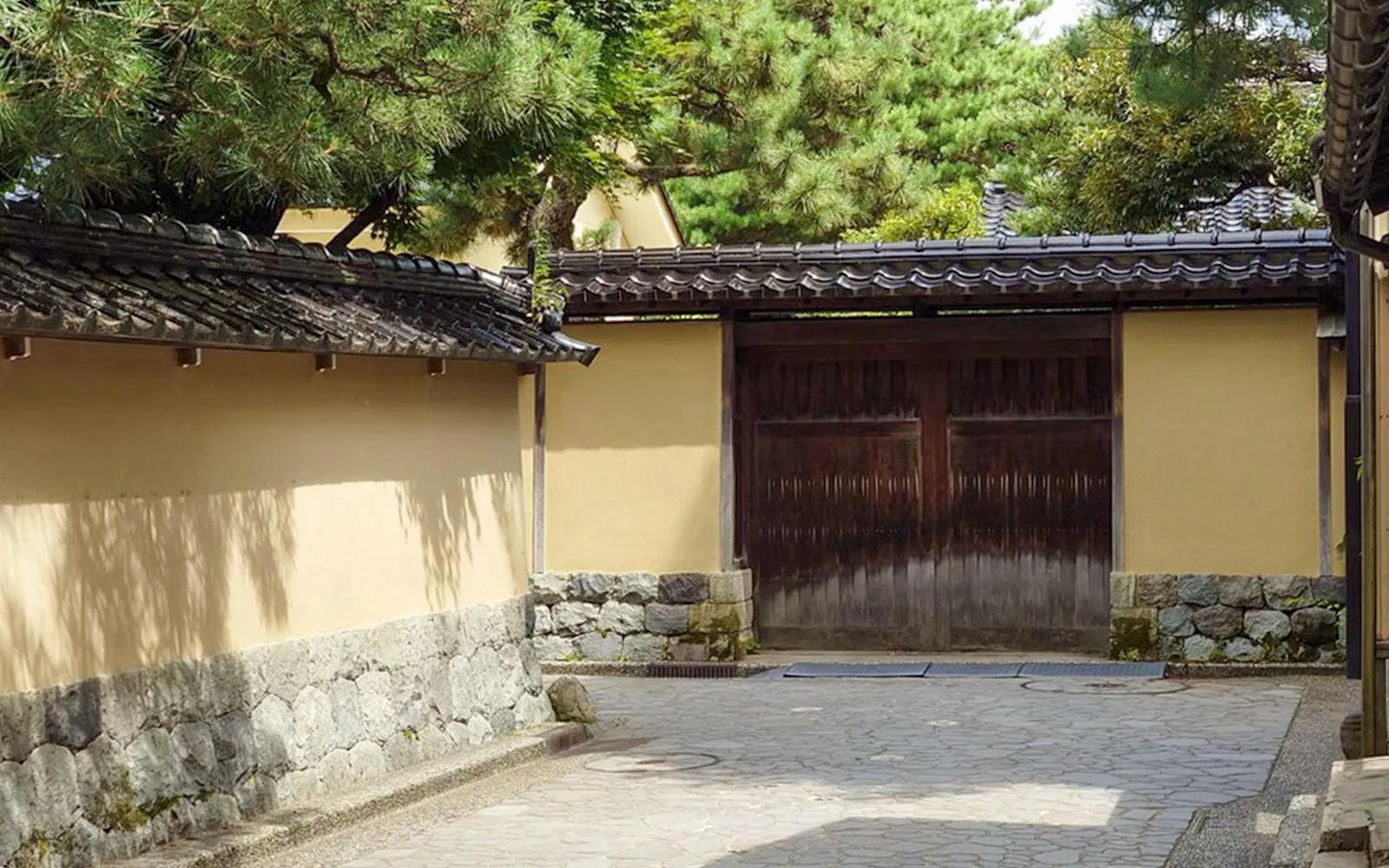 Traditional Japanese courtyard with stone walls and wooden gate in Kanazawa.