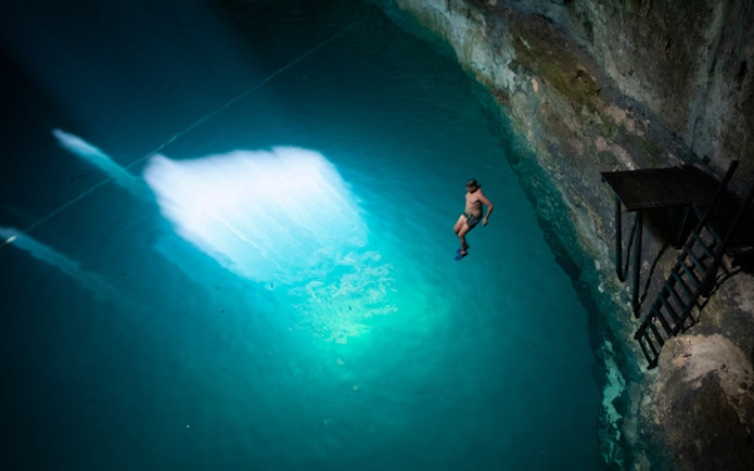 Person diving into a cenote during World Wonder Discovery Guided Tour.