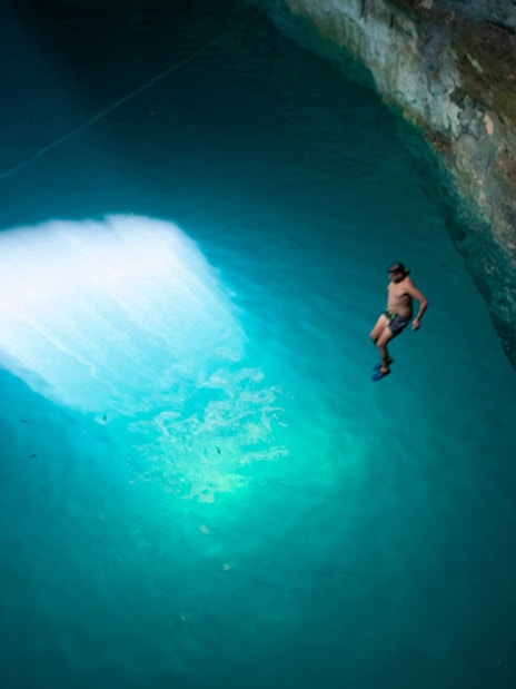Person diving into a cenote during World Wonder Discovery Guided Tour.