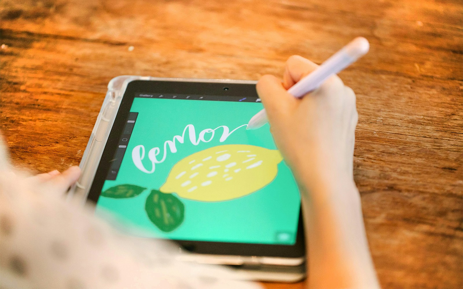 Woman drawing a lemon illustration on a tablet with a stylus.
