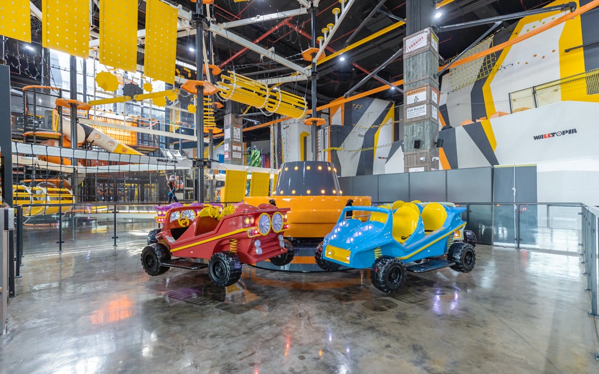 Indoor amusement park ride at Adrenark Adventure with colorful cars and climbing structures.