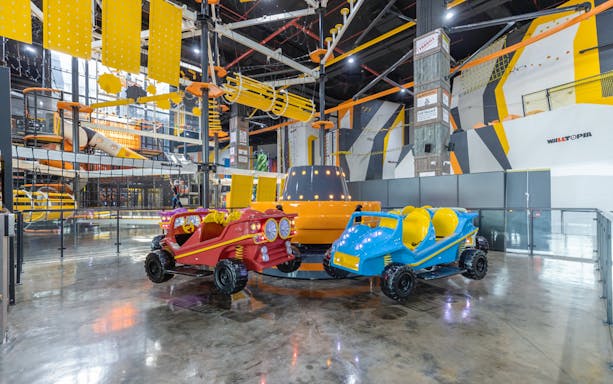 Indoor amusement park ride at Adrenark Adventure with colorful cars and climbing structures.