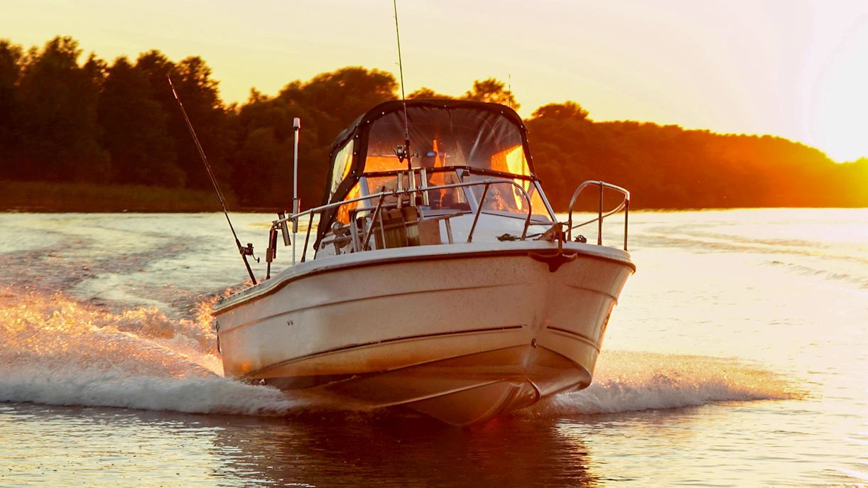 Motor boat cruising at sunset near Dubrovnik coastline.