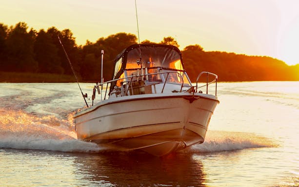 Motor boat gliding on water at sunset near Dubrovnik.