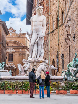 Fountain of Neptune in Piazza della Signoria, Florence, Italy with tourists observing.