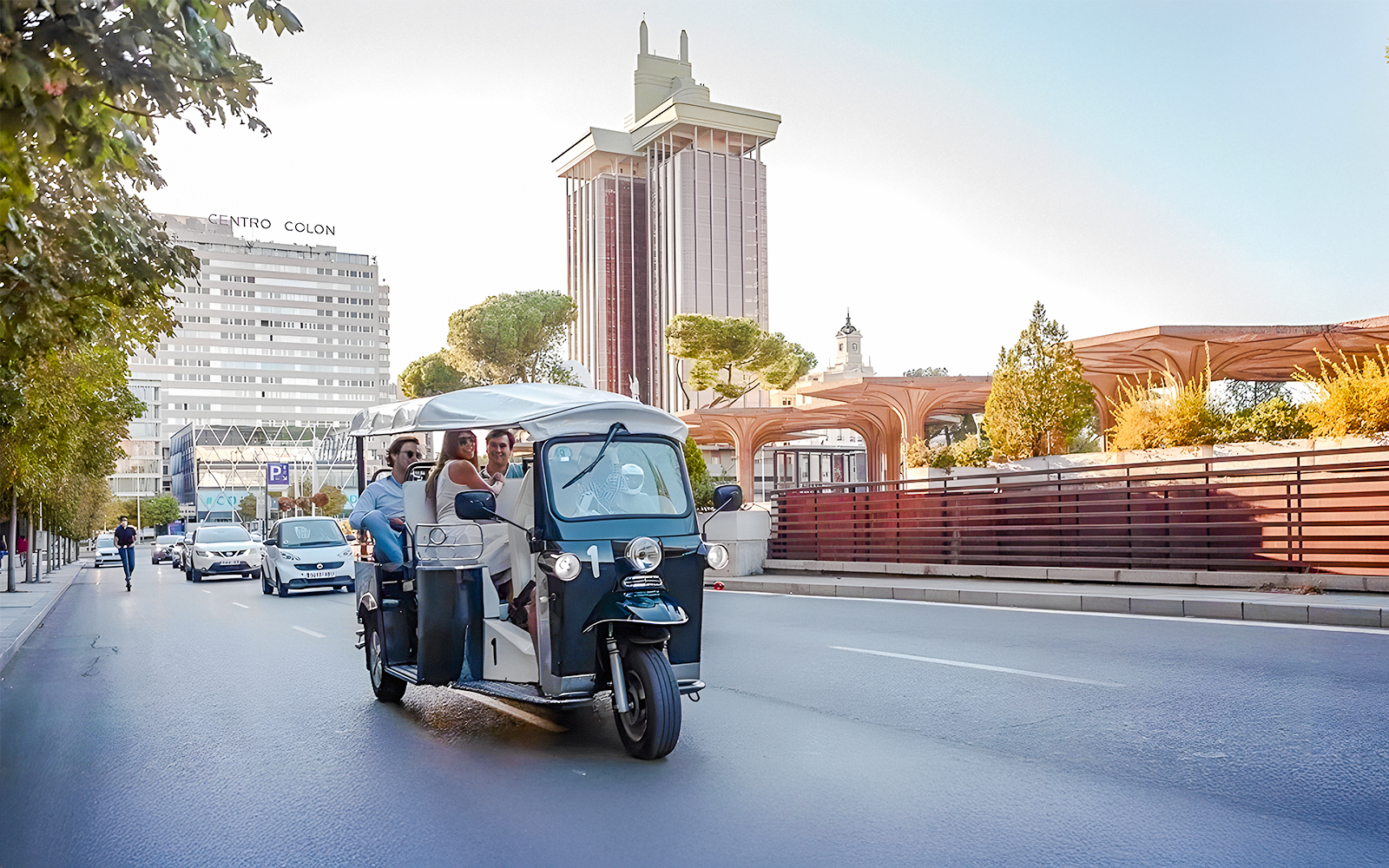 Electric tuk-tuk on Paseo de la Castellana, Madrid, with Torres de Colón in the background.