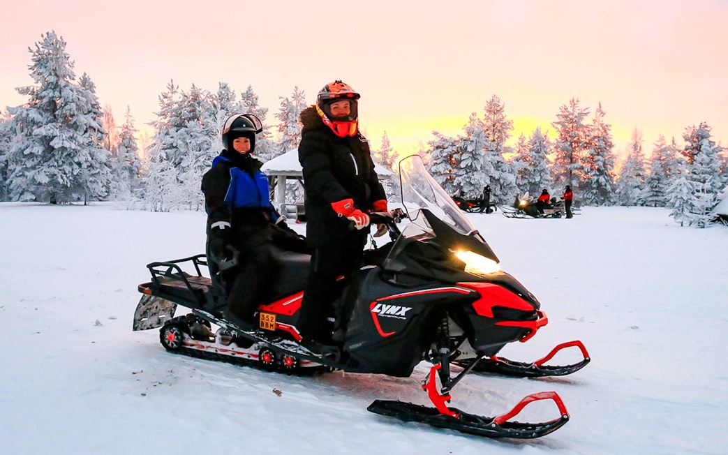 Guests on snowmobile during 1-Hour Safari Adventure in snowy Rovaniemi forest.