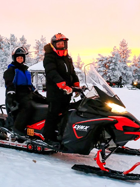 Guests on snowmobile during 1-Hour Safari Adventure in snowy Rovaniemi forest.