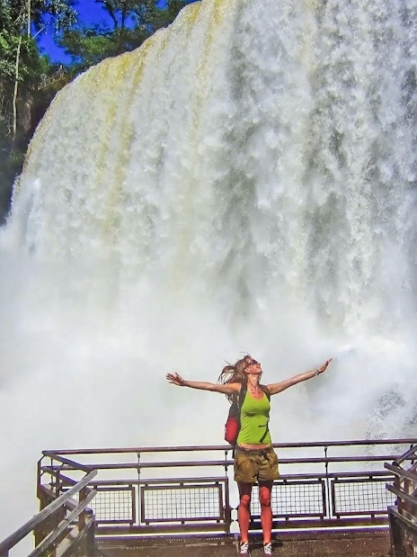 Visitor on a viewing platform at Iguazu Falls, Argentina, with cascading water in the background.