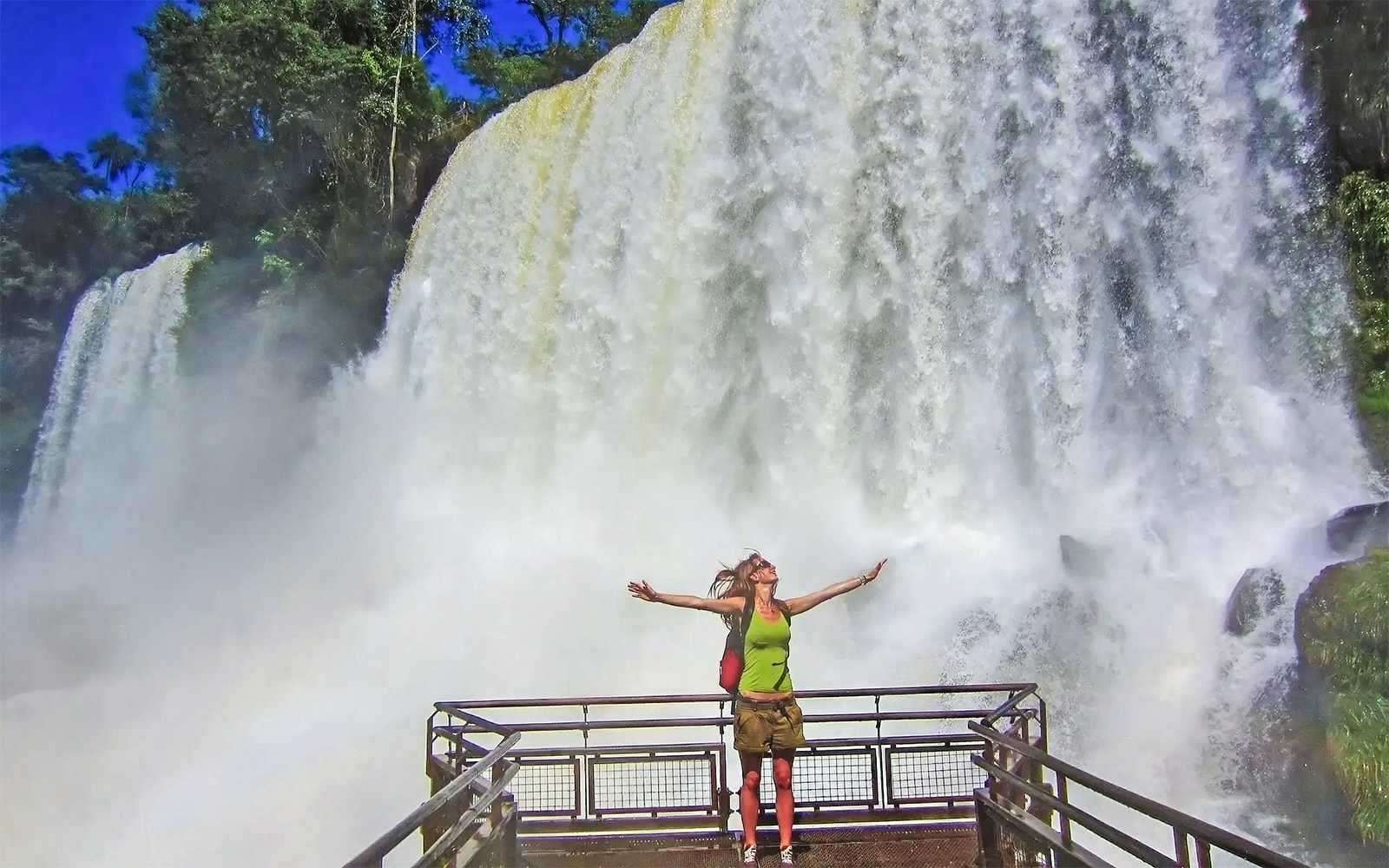 Visitor on a viewing platform at Iguazu Falls, Argentina, with cascading water in the background.