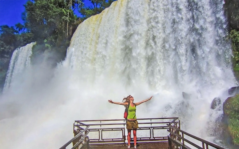 Visitor on a viewing platform at Iguazu Falls, Argentina, with cascading water in the background.