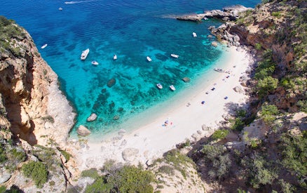 Aerial view of boats near a secluded beach on the Baunei Coast, Sardinia.
