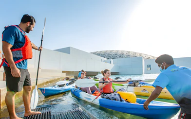 Visitors preparing for a guided kayak tour at Louvre Abu Dhabi.