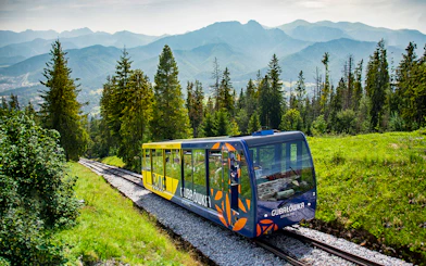 Funicular train ascending Gubałówka Hill in Zakopane with Tatra Mountains in the background.