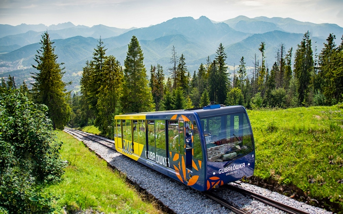 Funicular train ascending Gubałówka Hill in Zakopane with Tatra Mountains in the background.