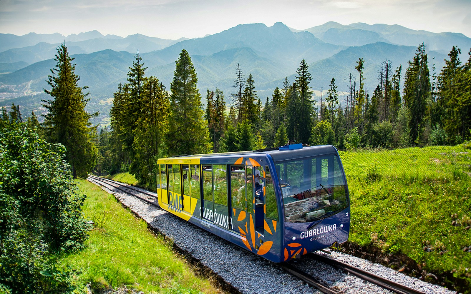 Funicular train ascending Gubałówka Hill in Zakopane with Tatra Mountains in the background.