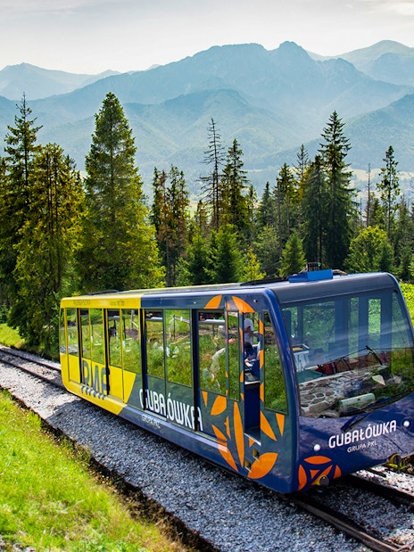 Funicular train ascending Gubałówka Hill in Zakopane with Tatra Mountains in the background.