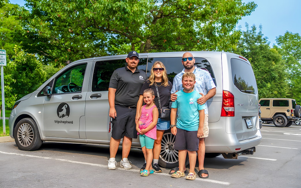 Family posing with tour van at Niagara Falls parking area.