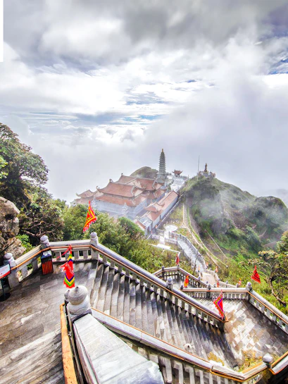 Staircase leading to Sun World Fansipan Legend with temple and pagoda in misty mountain landscape.