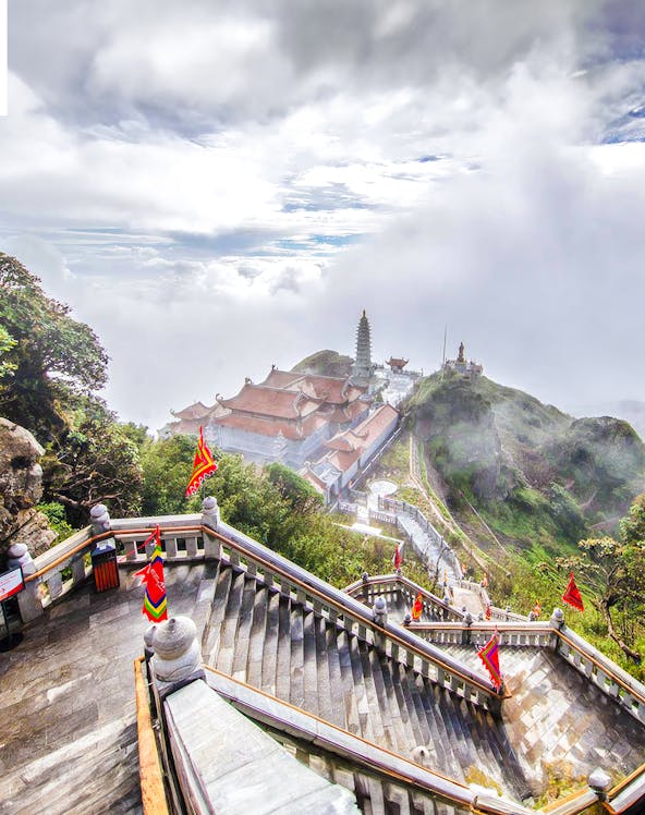Staircase leading to Sun World Fansipan Legend with temple and pagoda in misty mountain landscape.