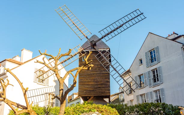 Moulin de la Galette windmill with people dining outdoors in Paris, France.
