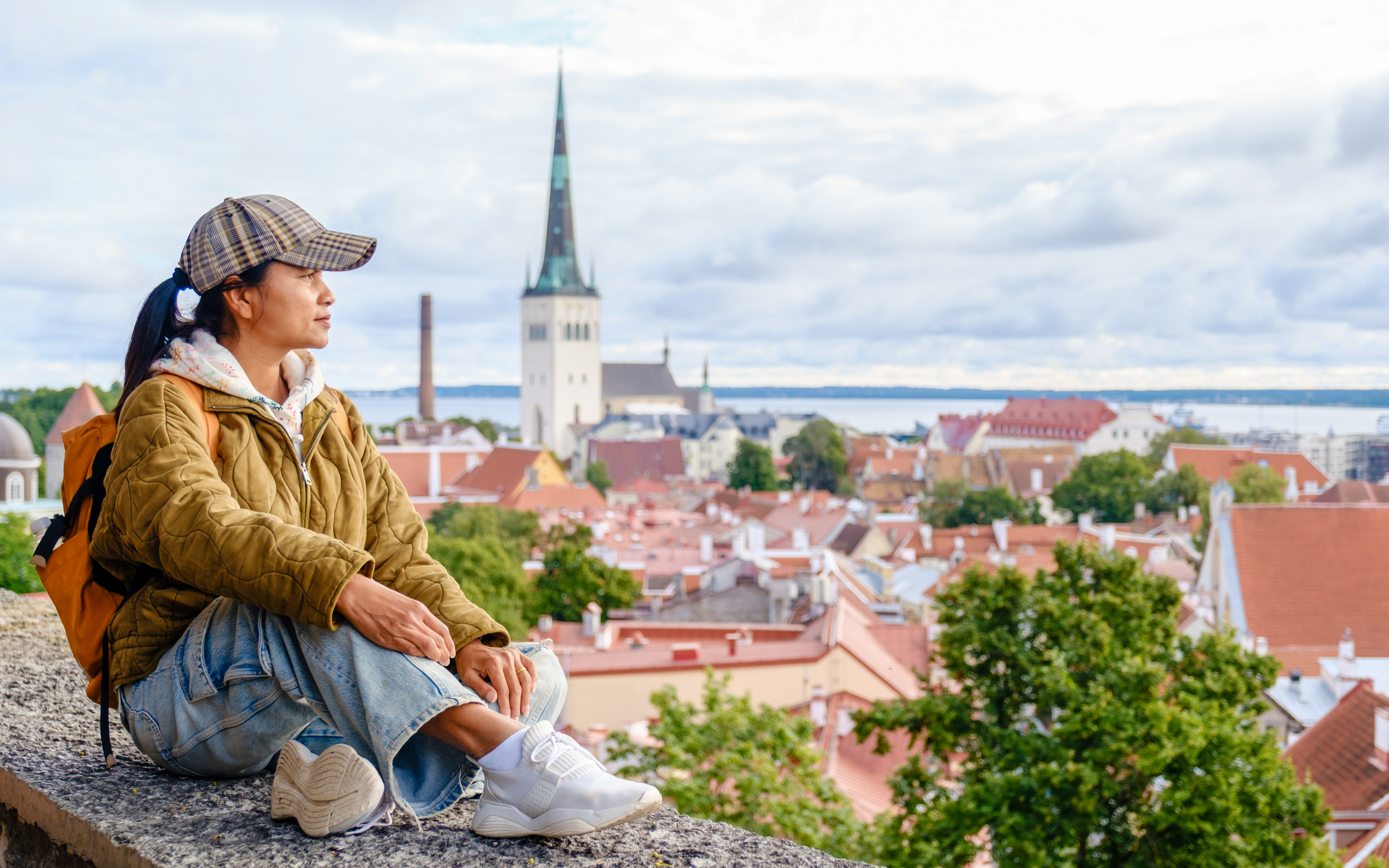 Traveler sitting at Kohtuotsa viewpoint overlooking Tallinn's old town, Estonia.
