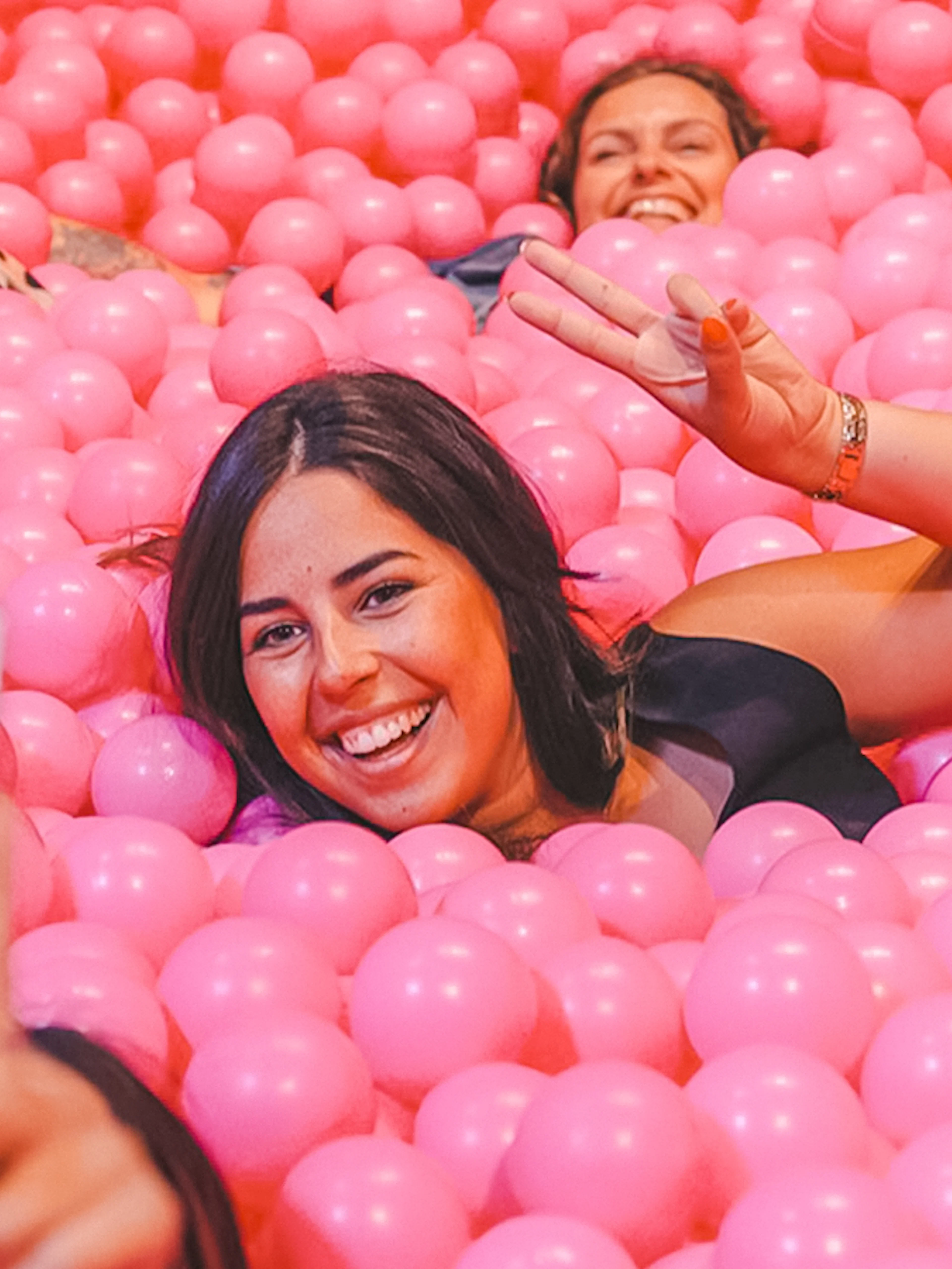 Visitors enjoying a ball pit at Pink Palace, taking a selfie.