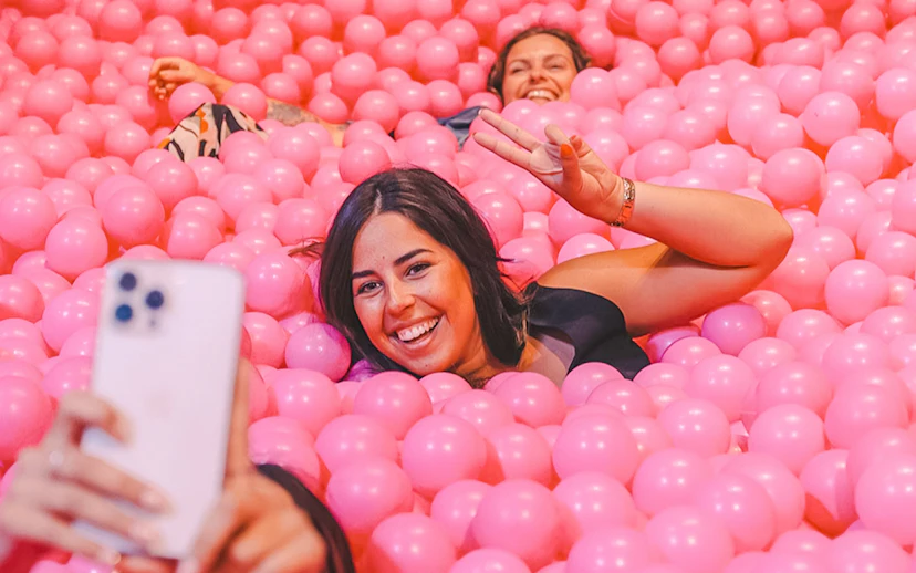 Visitors enjoying a ball pit at Pink Palace, taking a selfie.