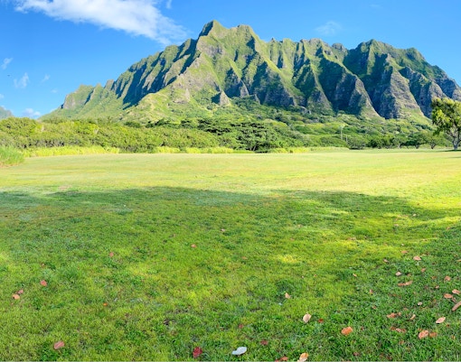 Kualoa Ranch landscape with lush green fields and mountain backdrop in Hawaii.