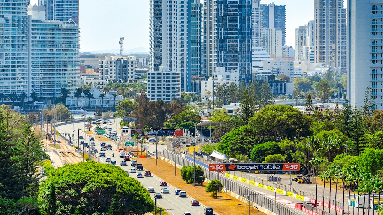 Gold Coast highway with city skyscrapers and lush greenery in the background.