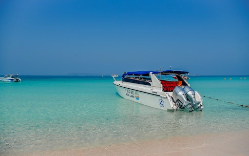 Speedboat anchored on Pattaya Island beach, clear turquoise water, Thailand.