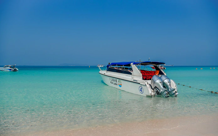 Speedboat anchored on clear waters of Koh Larn, Pattaya, for island day trip activities.