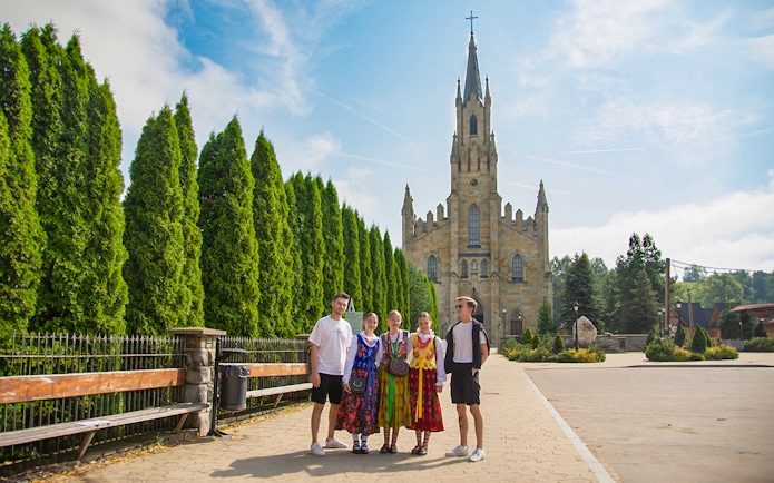 Guests in traditional attire posing near a historic church with tall spires.