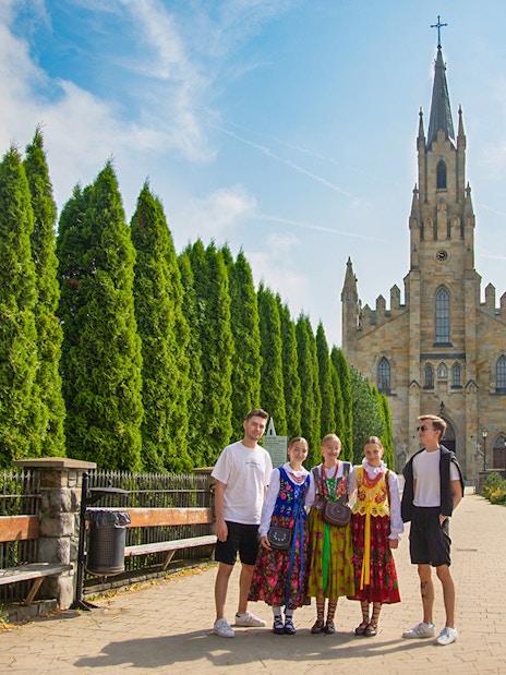Guests in traditional attire posing near a historic church with tall spires.