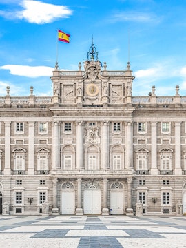 Royal Palace of Madrid facade with Spanish flag, Madrid, Spain.