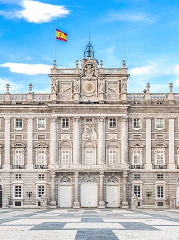 Royal Palace of Madrid facade with Spanish flag, Madrid, Spain.