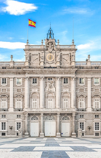 Royal Palace of Madrid facade with Spanish flag, Madrid, Spain.