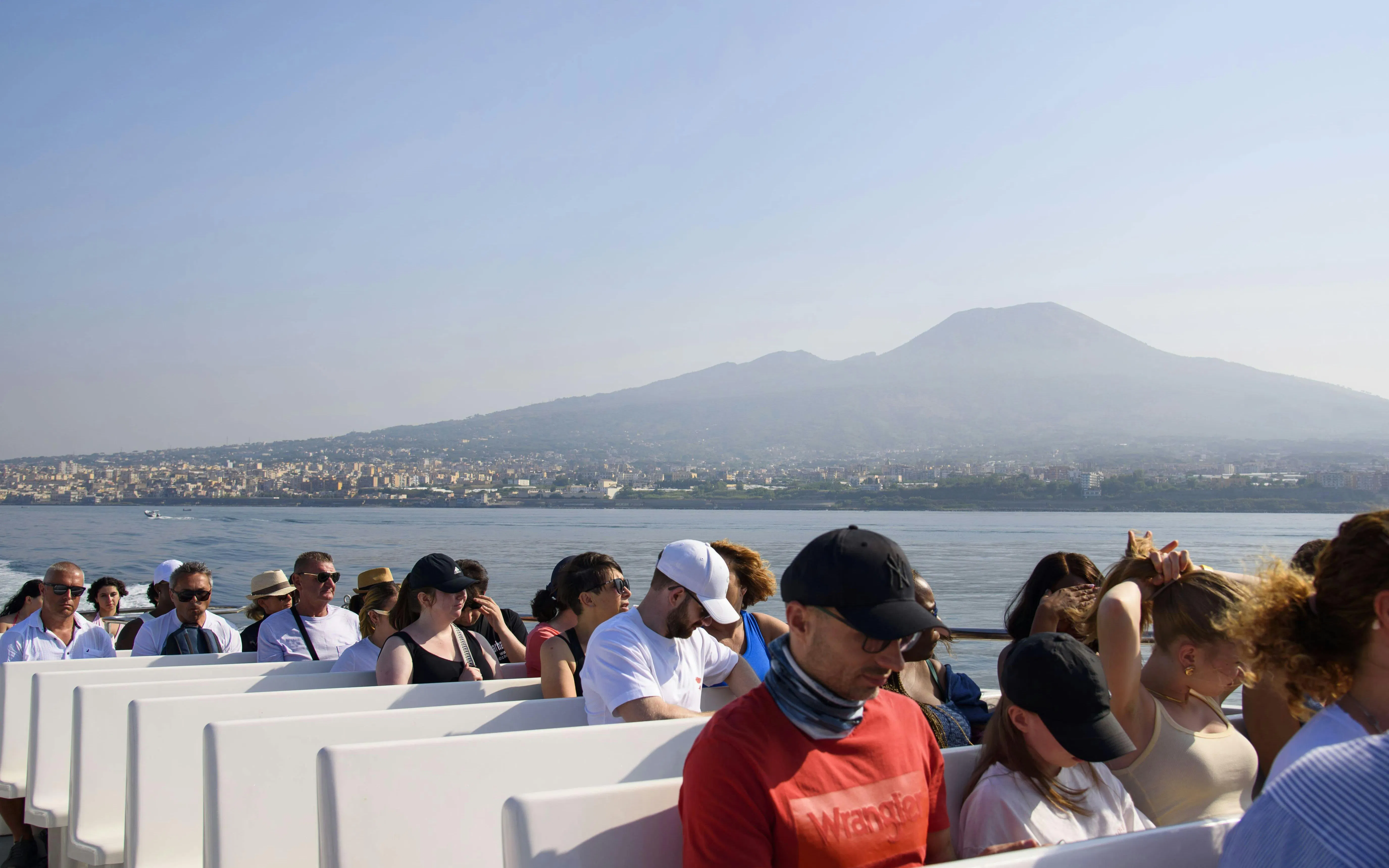 Tourists on a boat with Mount Vesuvius in the background during an Amalfi Coast cruise.