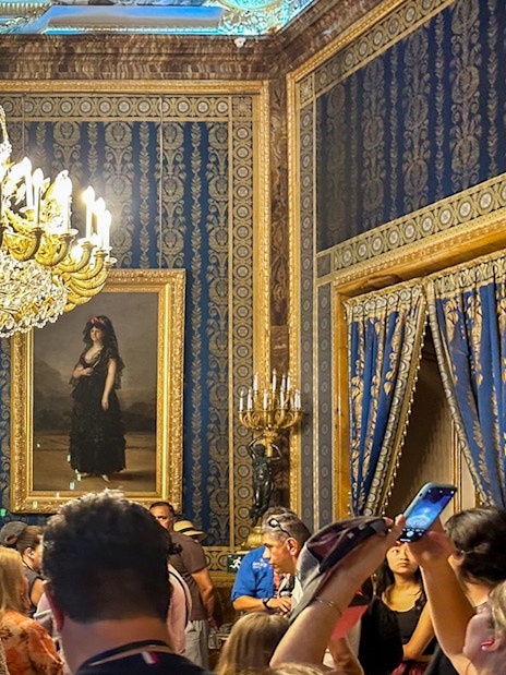 Royal Palace of Madrid tour group under ornate chandelier in opulent room.