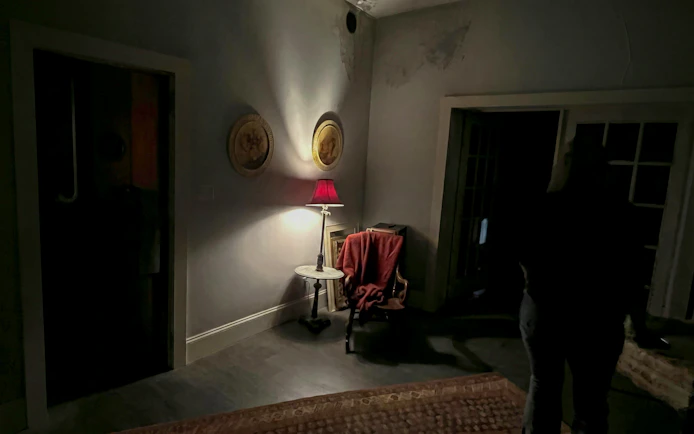 Dimly lit room with red lamp and chair, part of Savannah paranormal investigation tour.
