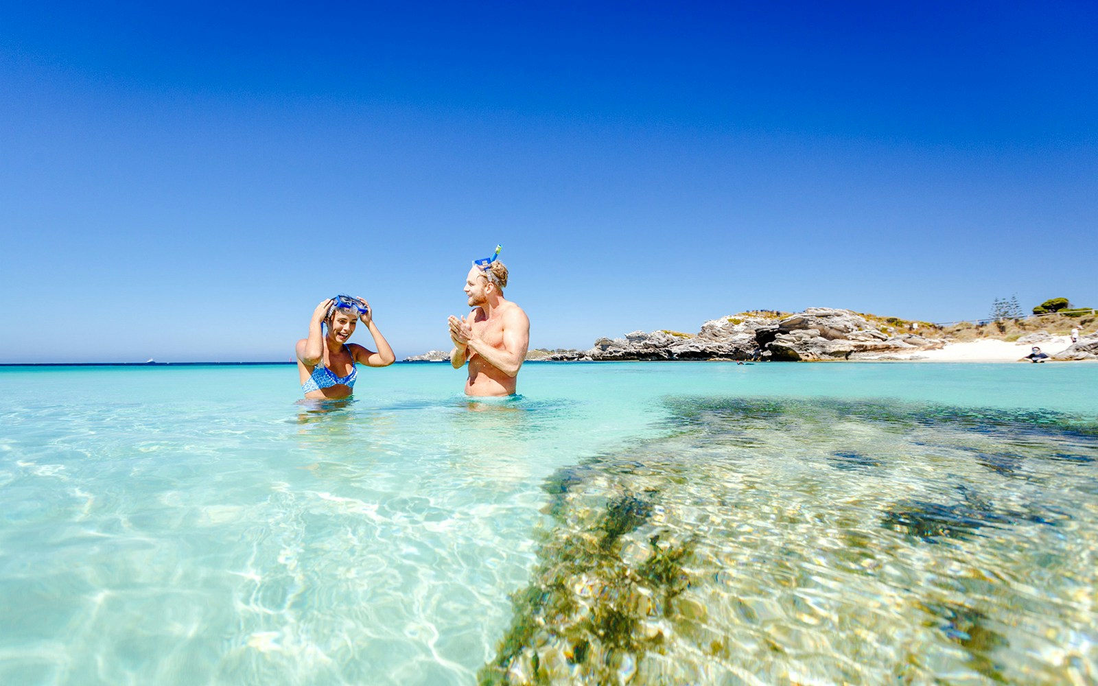Couple snorkeling in clear turquoise water at Rottnest Island, Australia.