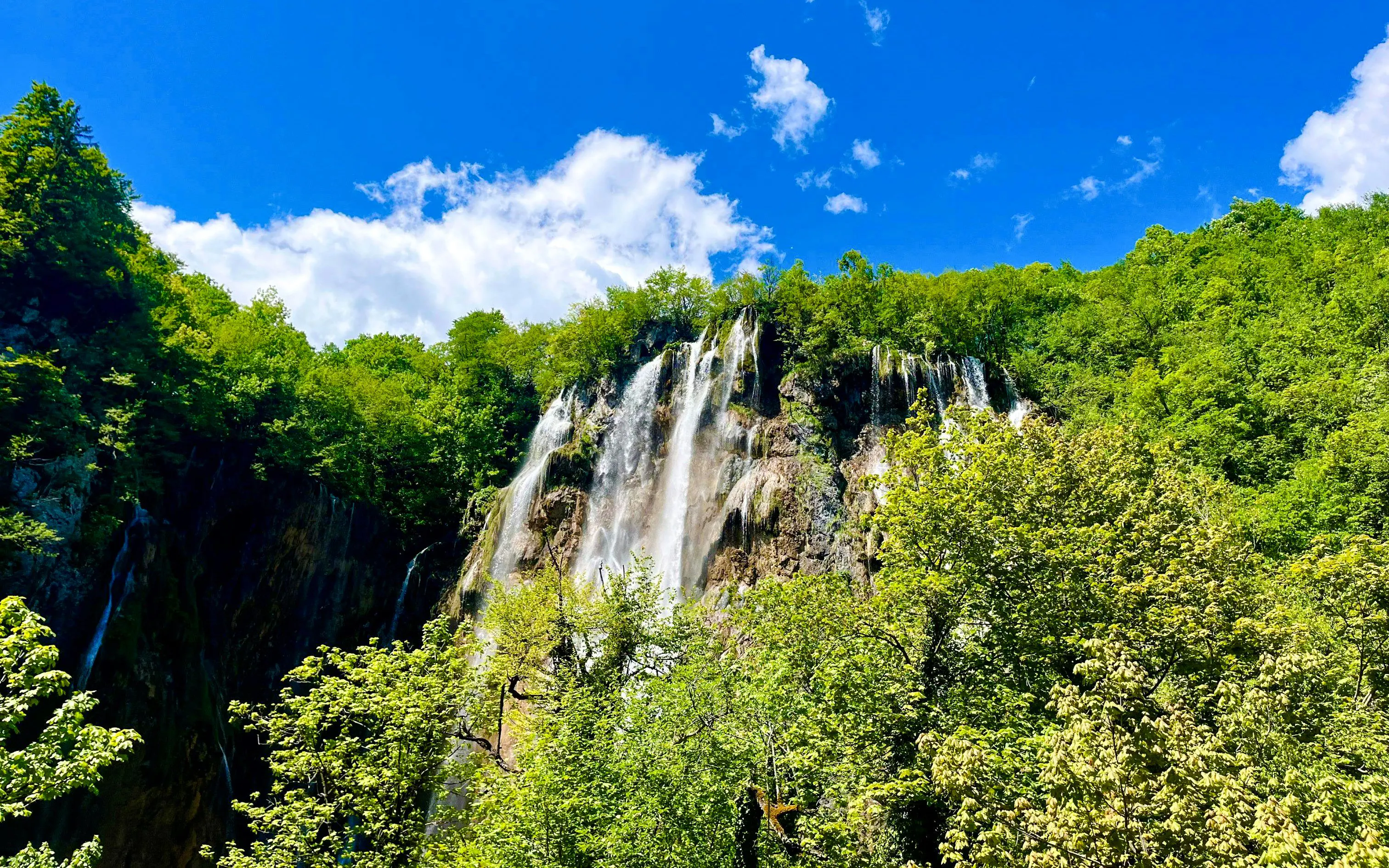 Aerial view of waterfalls surrounded by lush greenery in Plitvice National Park, Croatia.
